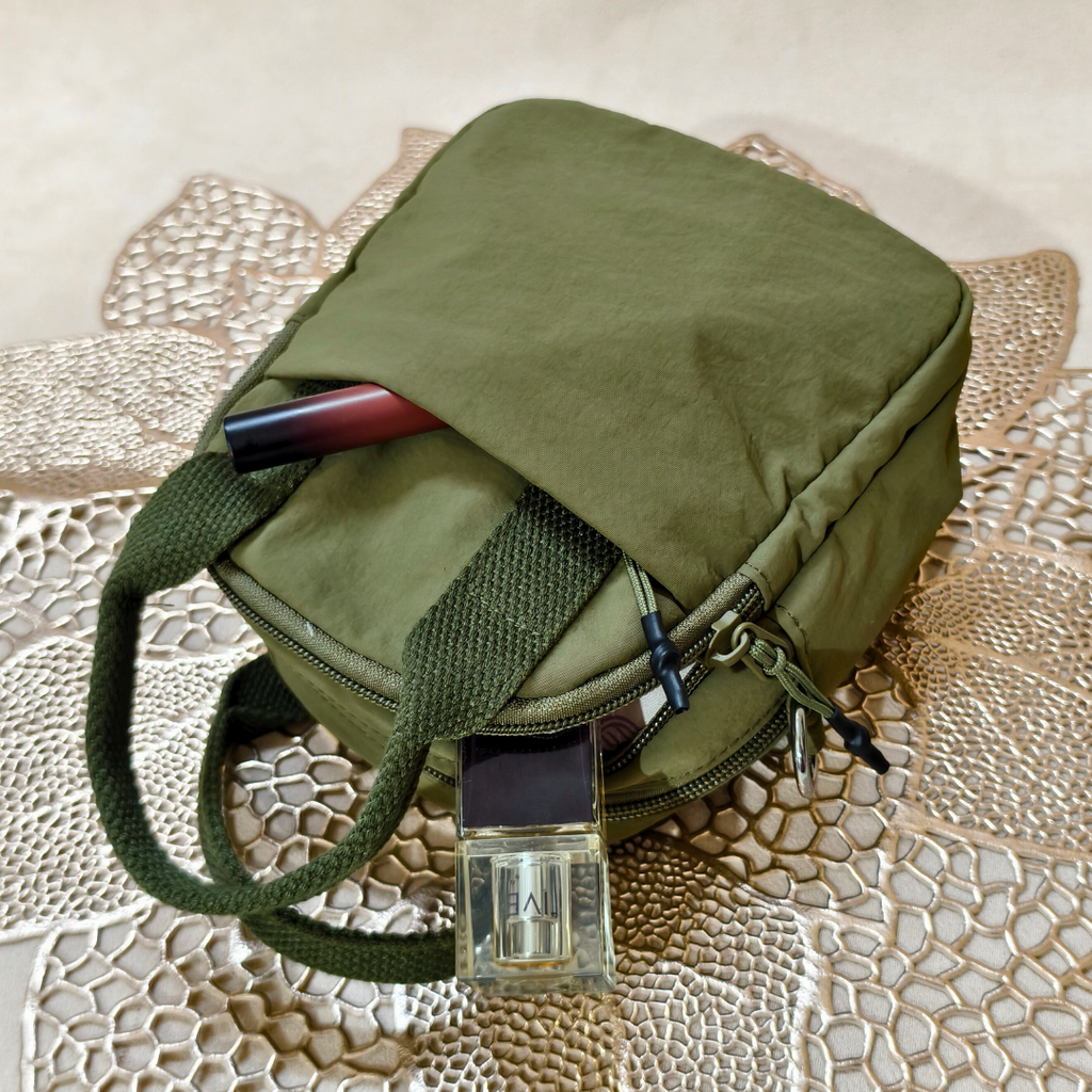 Green bag with a belt and pen on a textured surface