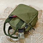 Green bag with a belt and pen on a textured surface