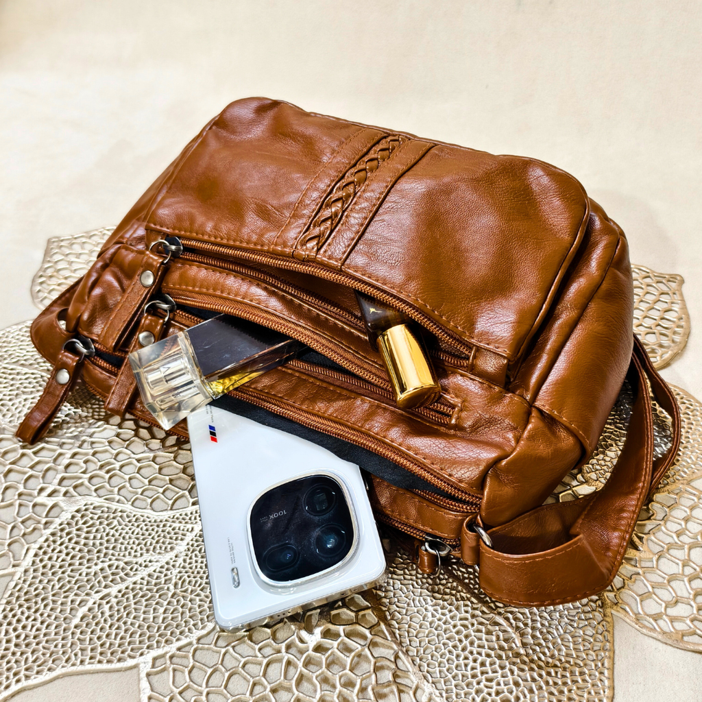 Brown leather bag with a phone inside on a textured surface