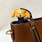 Cartoon dog-shaped phone case peeking out of a brown leather bag
