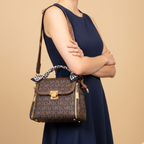 Woman holding a brown handbag with gold accents against a beige background