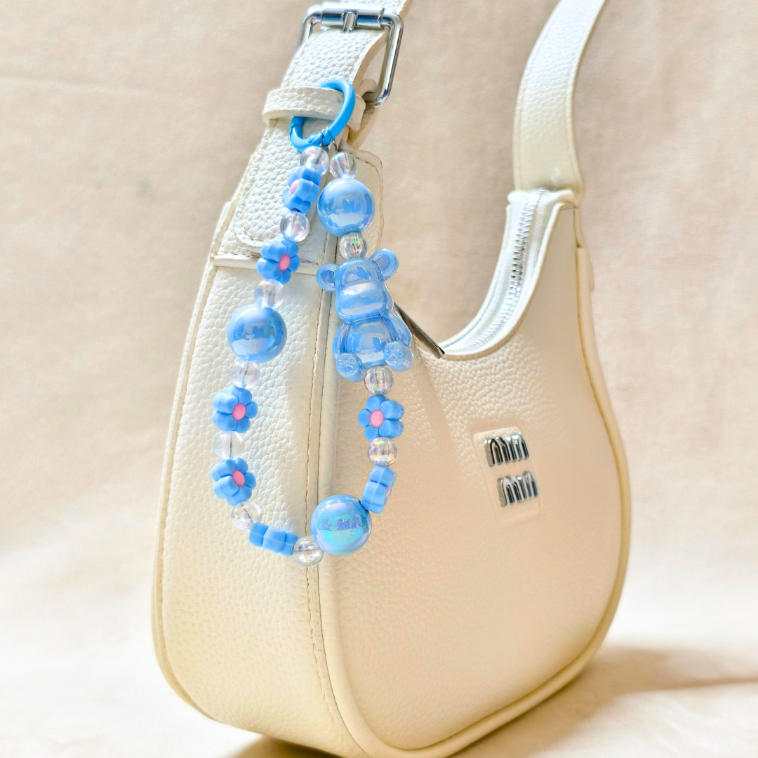 Blue beaded strap extender attached to a beige handbag
