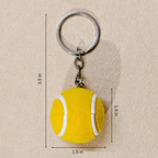 A yellow felt tennis ball keychain with a silver metal split ring and chain, shown on a beige textured background with dimension lines indicating measurements of 1.5 inches in diameter and 3.
