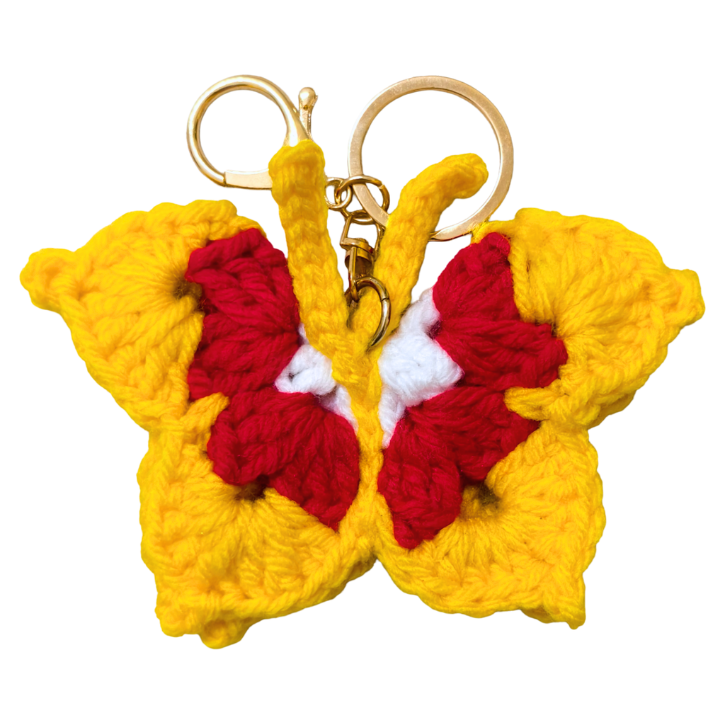 Crocheted butterfly keychain with yellow wings and red center on a white background