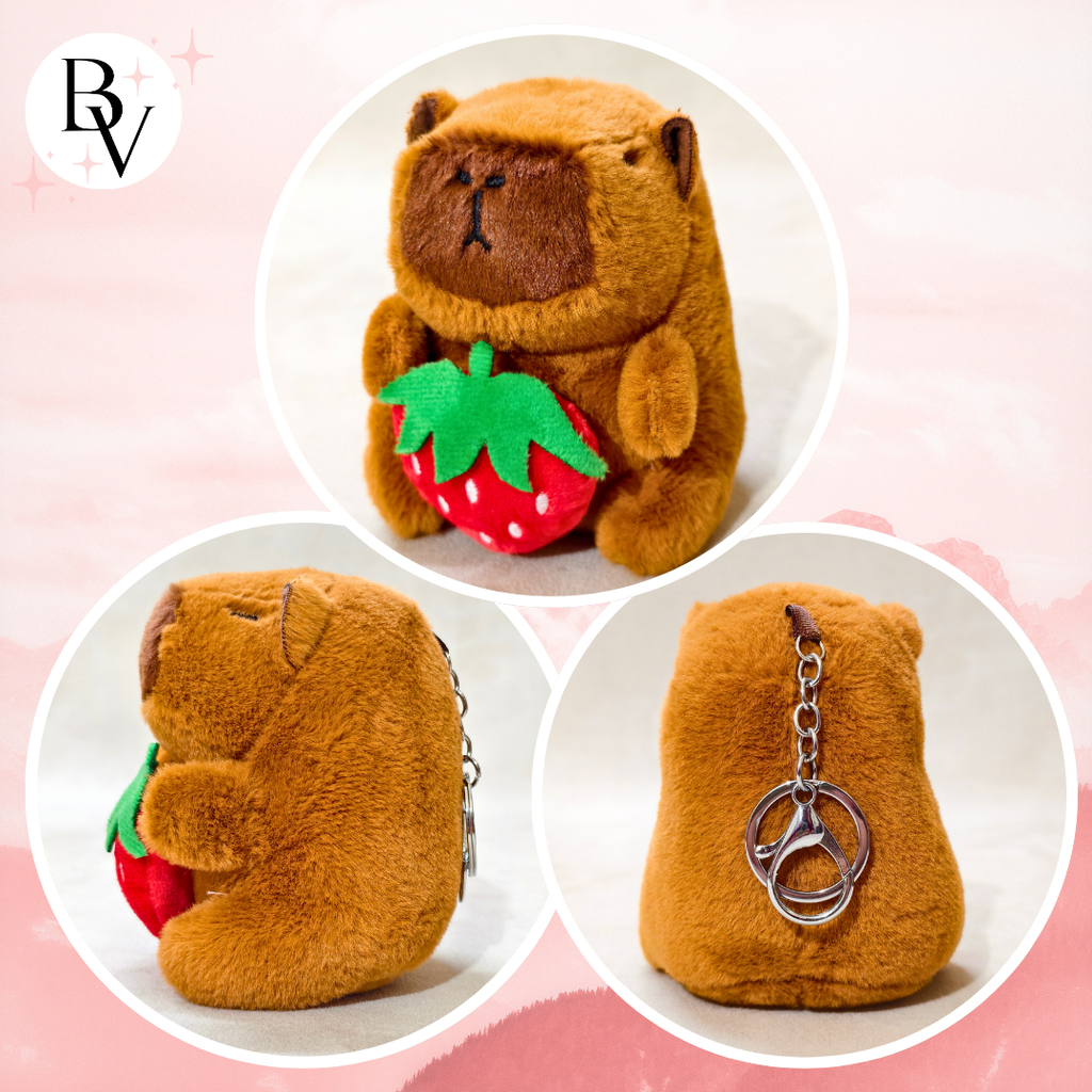 Plush bear toy with a strawberry and keychain on a pink background