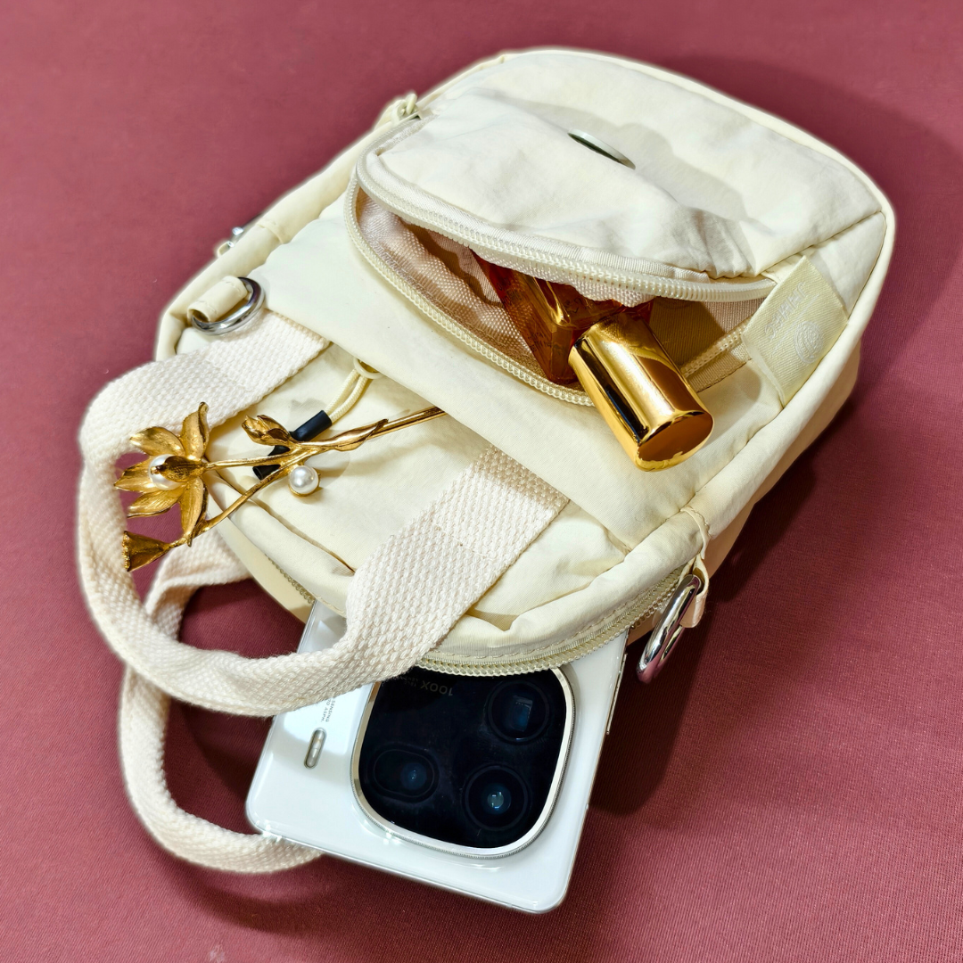 White phone case with gold accents and jewelry on a pink background