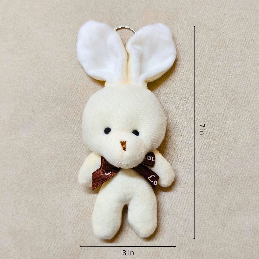 White plush bunny keychain with a brown bow tie on a beige background, showing measurements.