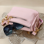 Pink handbag with gold accents and sunglasses on a textured surface