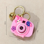 Pink cartoon camera keychain with bell on beige background