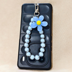 Phone case with blue flower charm on a beige background