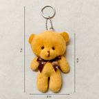 Yellow teddy bear keychain with dimensions on a beige background