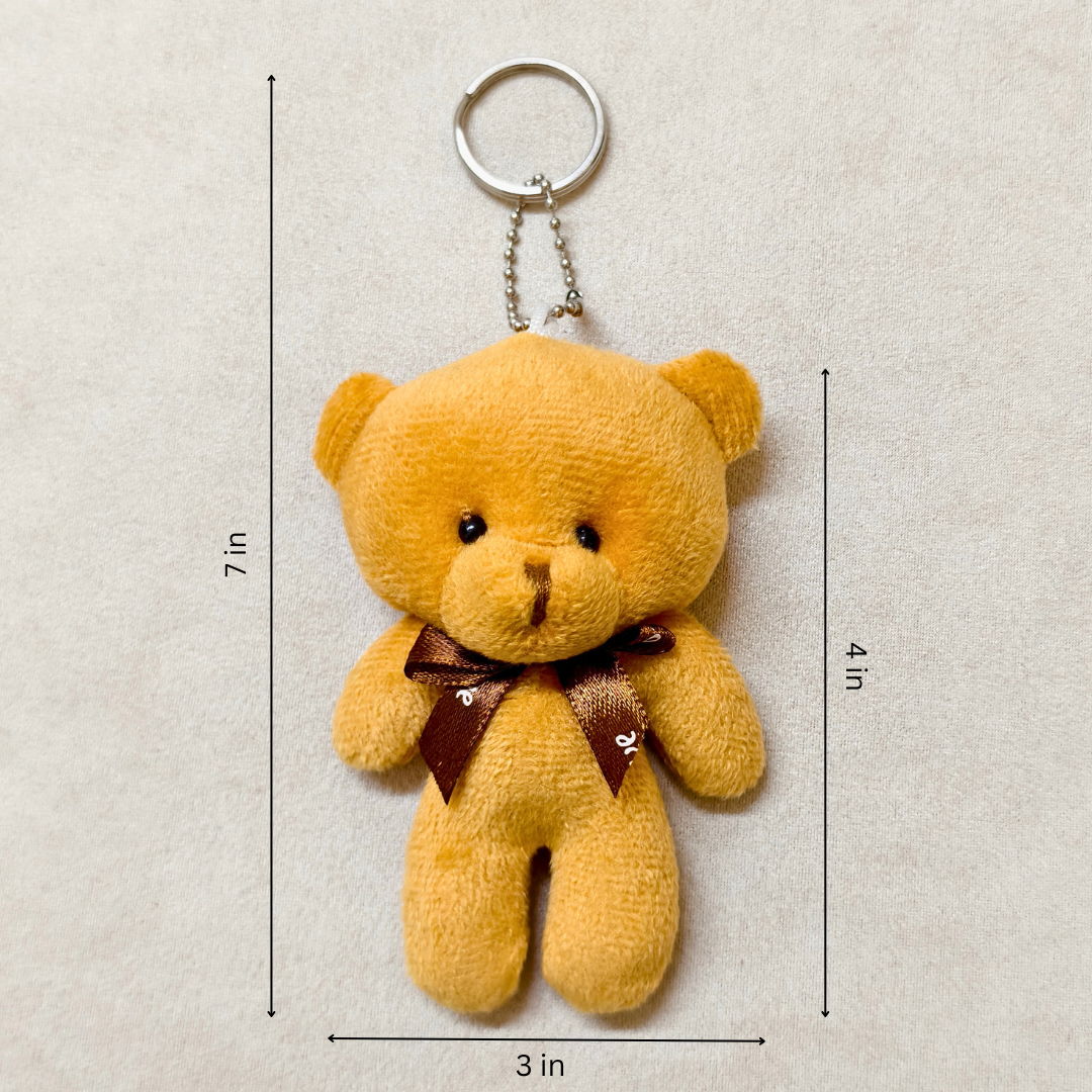 Yellow teddy bear keychain with dimensions on a beige background