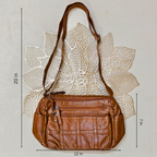 Brown leather handbag with measurements on a textured beige background