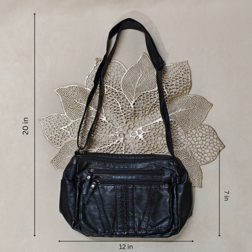 Black leather handbag with measurements on a textured beige background