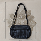 Black leather handbag with measurements on a textured beige background