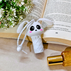 White cartoon-style ice cream cone with bunny ears on a book with flowers and a perfume bottle.