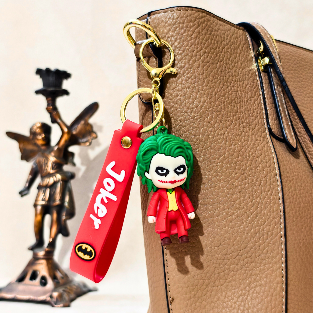 Keychain with 'Joker' character attached to a bag, with a statue in the background.