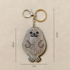 Keychain with rhinestone design of a small creature, shown with measurements on a beige background
