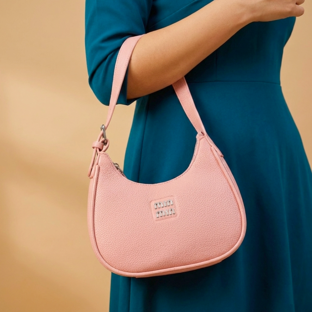 Pink handbag held by a person wearing a teal dress against a beige background