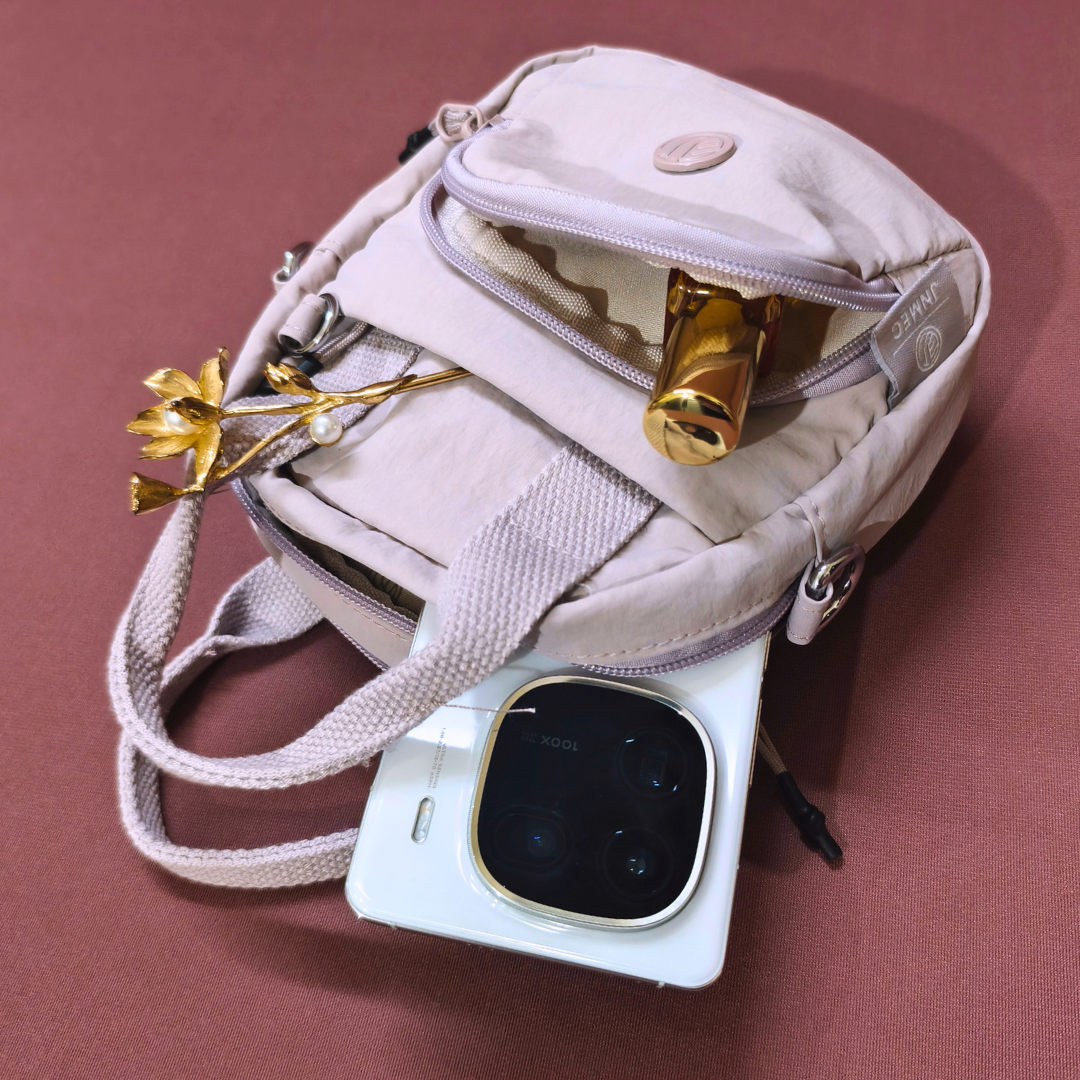 White handbag with gold accents on a pink background