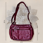 Maroon handbag with measurements on a textured beige background