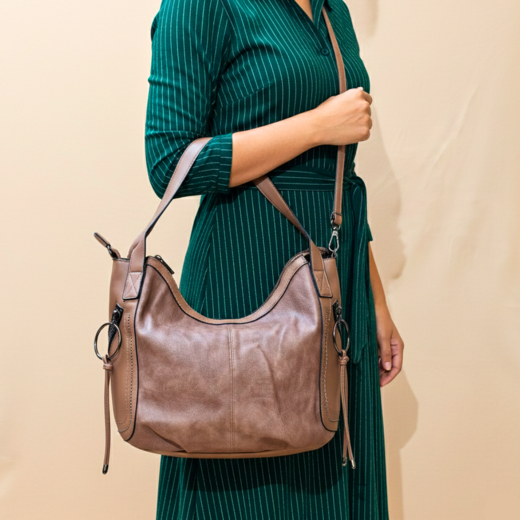 Person wearing a green dress holding a brown leather handbag against a beige background