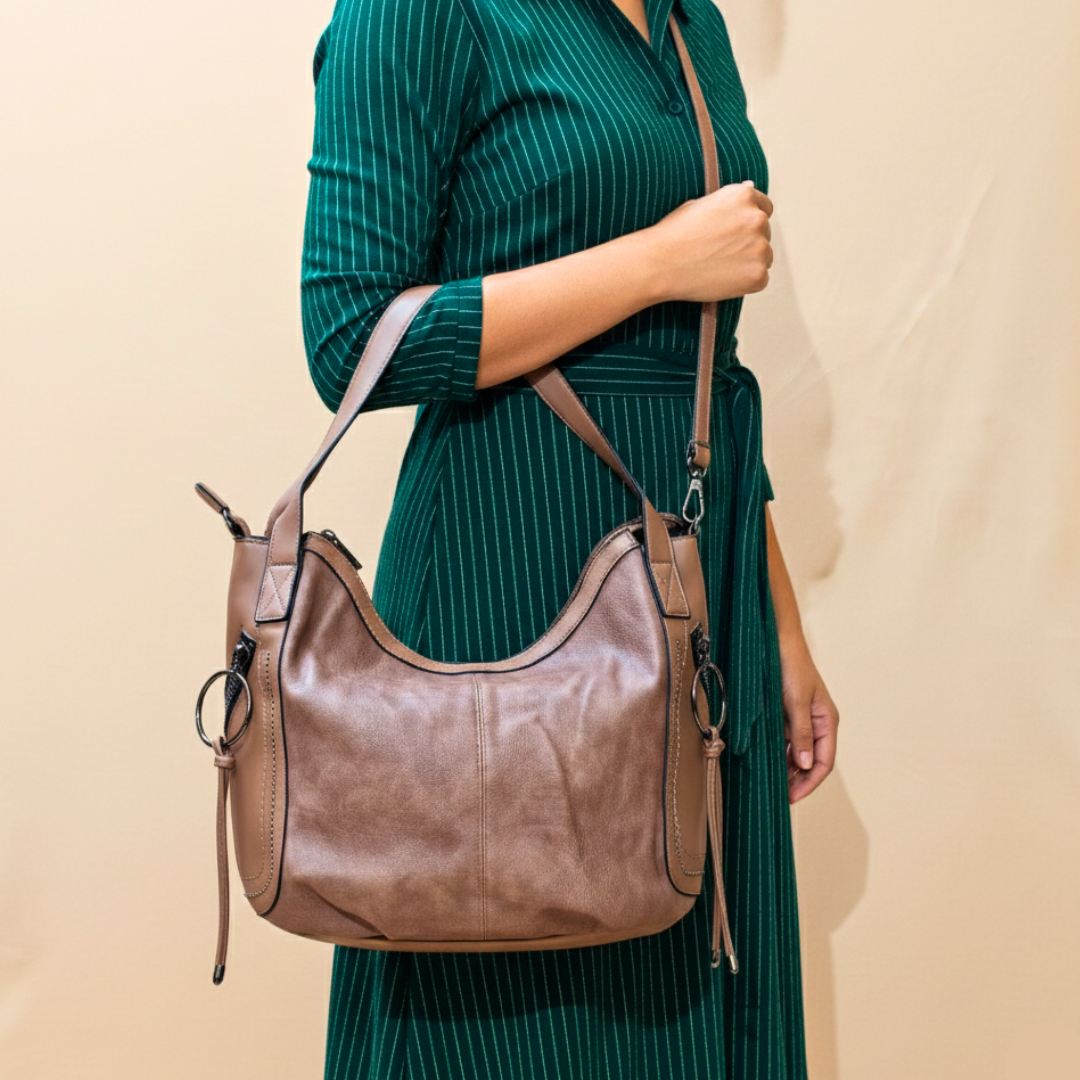Person wearing a green dress holding a brown leather handbag against a beige background
