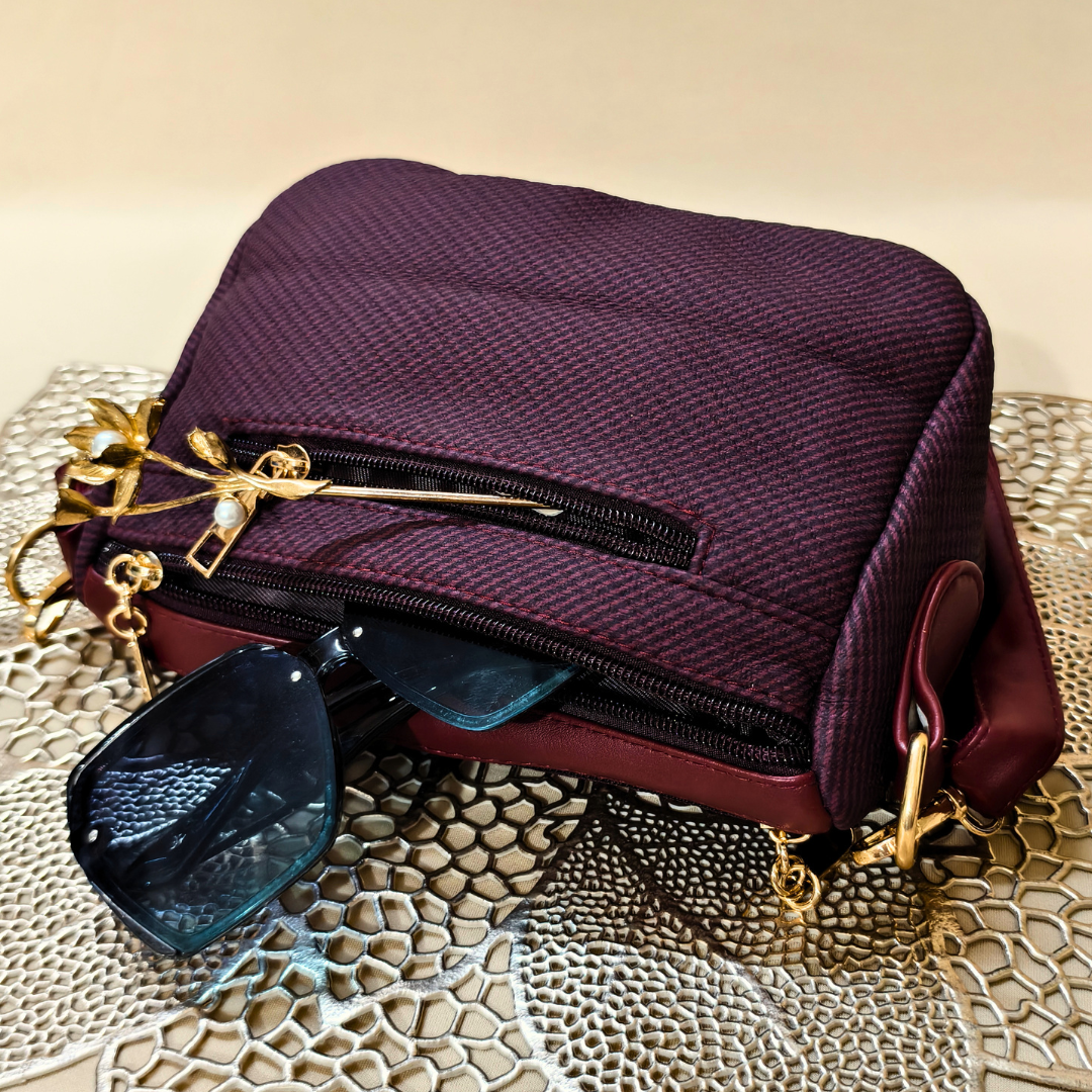 Purple handbag with gold accents on a textured surface