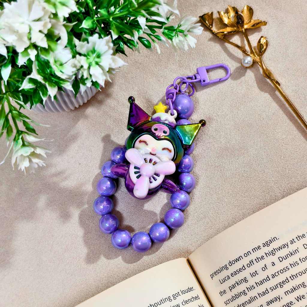 Colorful beaded keychain with character design on a book next to flowers and a gold flower arrangement.