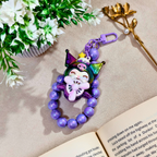 Colorful beaded keychain with character design on a book next to flowers and a gold flower arrangement.