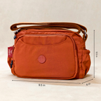 Rust Brown Sling Bag With Measurements In Front Of Beige Background.