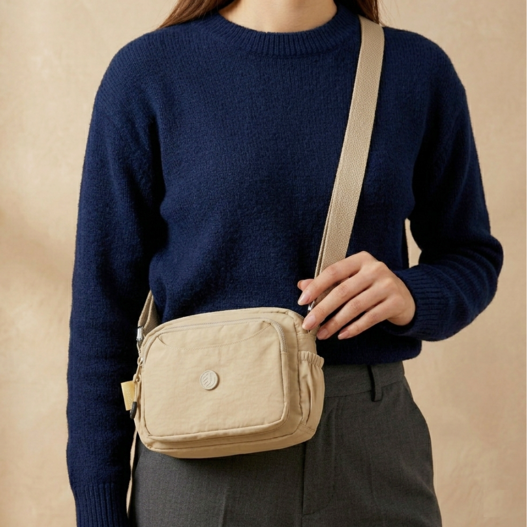 Model Carrying Khaki Beige Sling Bag In Front Of Beige Background.