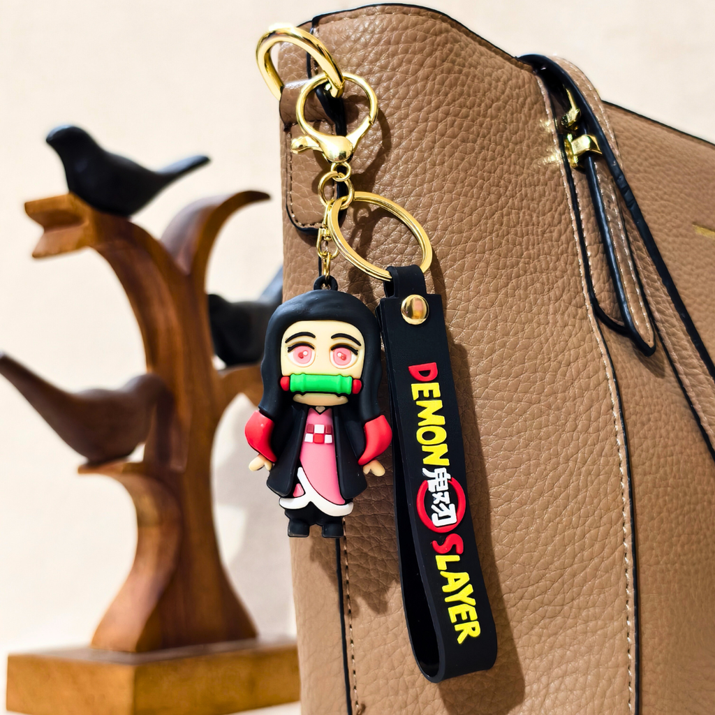Nezuko Character Keychain latched onto a beige purse alongside a bird prop in front of a beige background
