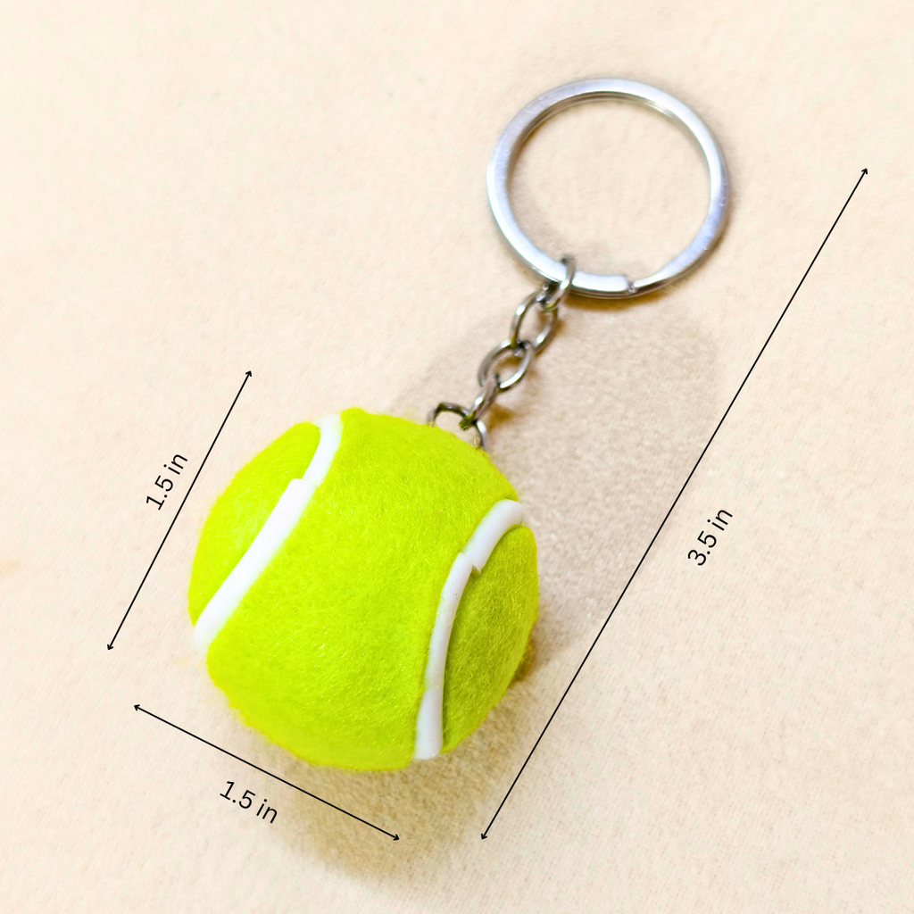 A tennis ball keychain with a bright yellow-green felt ball and silver metal key ring, shown on a beige background with dimension lines and text indicating measurements of 1.5 in by 3.