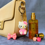 Hello Kitty keychain, perfume bottle, and small bottles on a textured surface with a beige handbag in the background.
