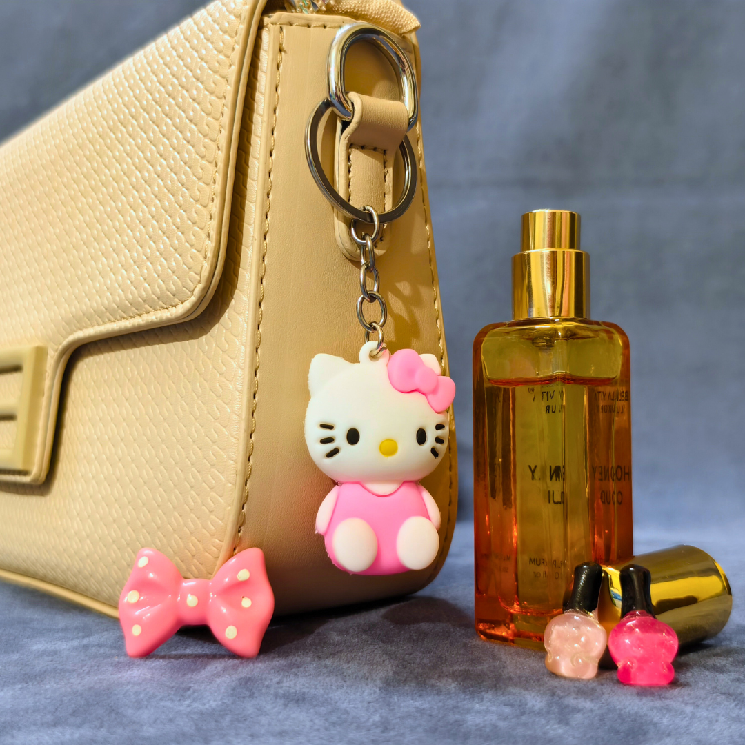 Hello Kitty keychain, perfume bottle, and small bottles on a textured surface with a beige handbag in the background.