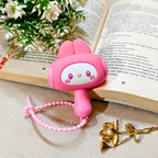 Pink cartoon character bookmark on an open book with flowers and a brooch.