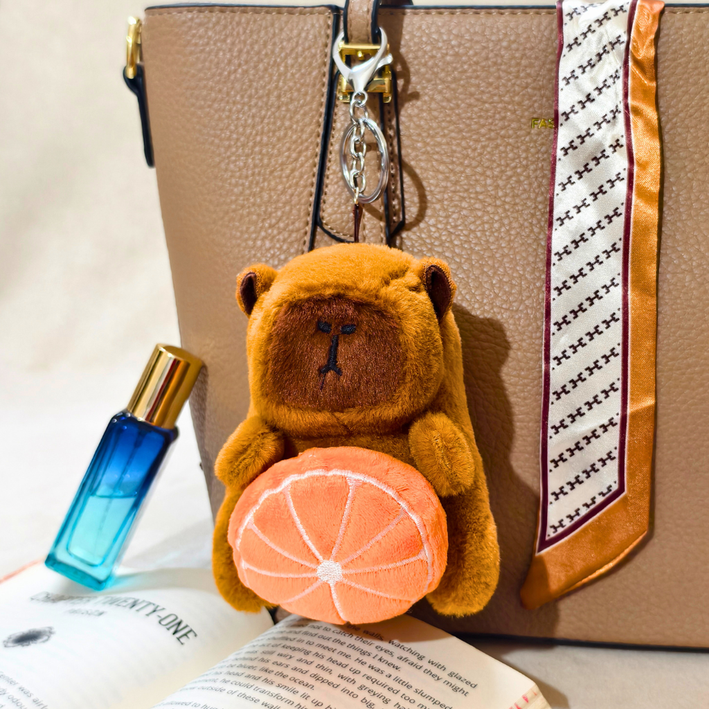 Teddy bear keychain with an orange design attached to a handbag.