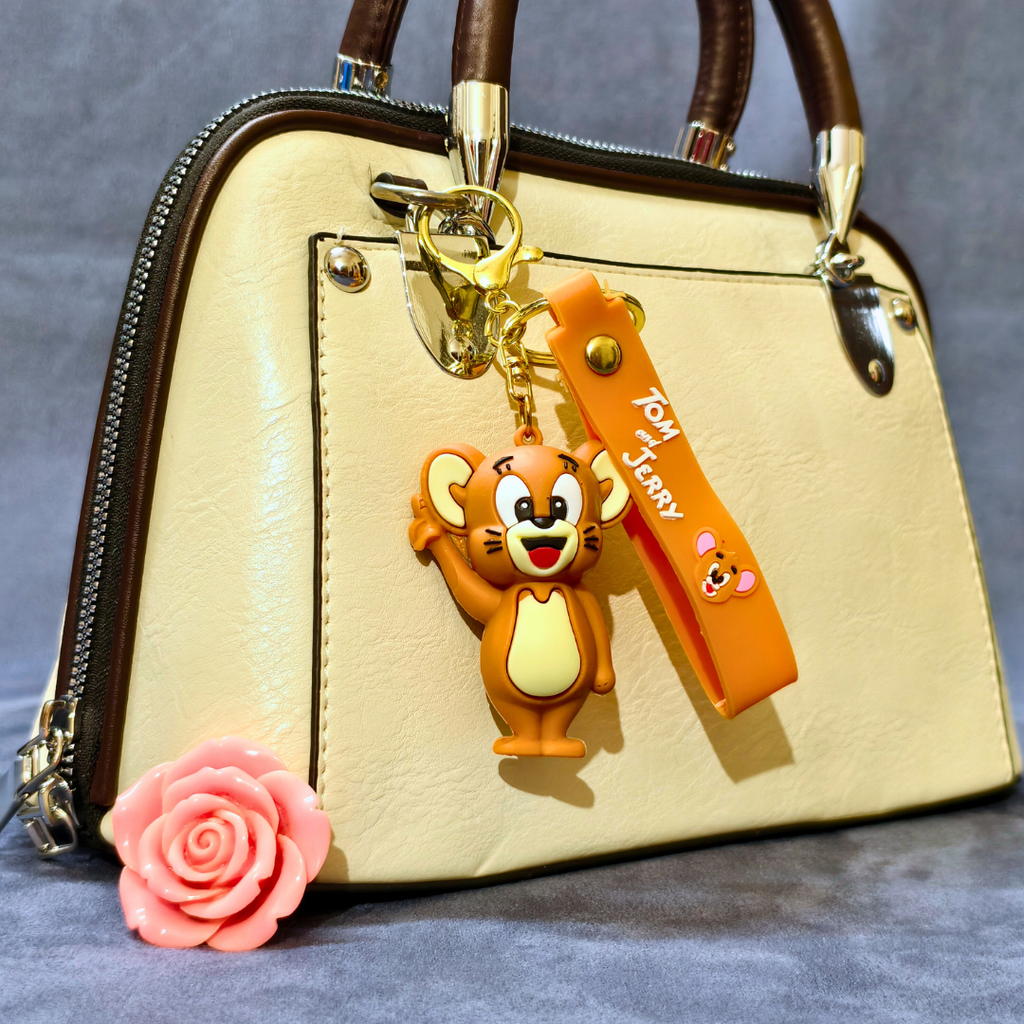 Beige handbag with a cartoon character keychain and pink flower on a gray background