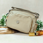 Khaki Beige Sling Bag With Props In Front Of Beige Background.