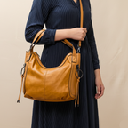 Person holding a tan leather handbag against a beige background