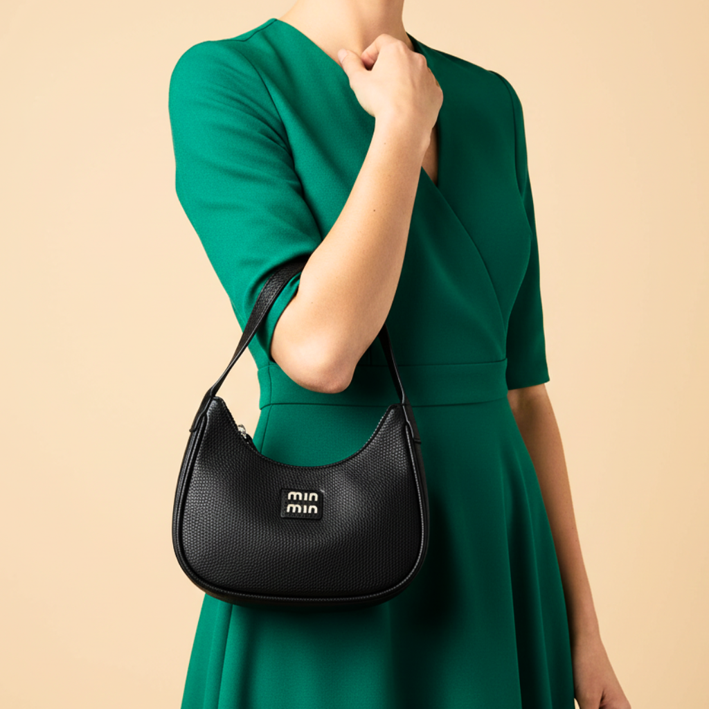Person wearing a green dress holding a black handbag with 'miu miu' logo on a beige background