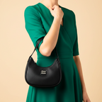 Person wearing a green dress holding a black handbag with 'miu miu' logo on a beige background