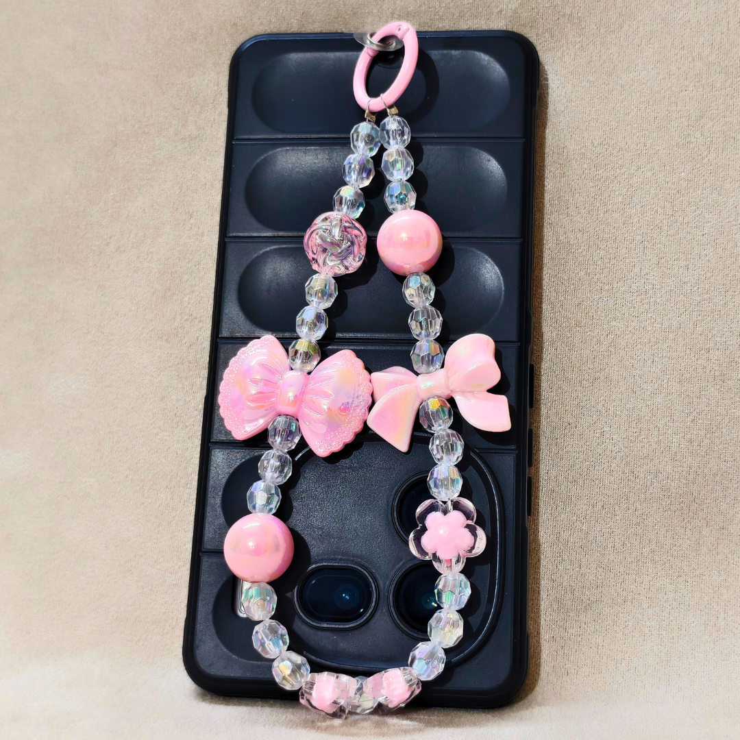 Pink Bow Charm Attached on Phone In Front Of Beige Background.