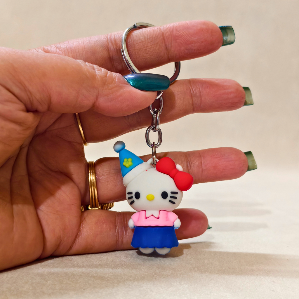 Hand holding a keychain with a cartoon character wearing a blue hat and pink dress.