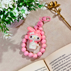 Pink character charm with beads on a book with flowers and gold leaf in the background