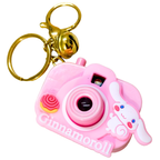 Pink camera-shaped keychain with a gold ring on a white background