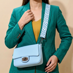 Person wearing a teal blazer with a light blue handbag featuring a zigzag strap.