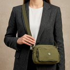Model Carrying Military Green Sling Bag In  Front Of Beige Background.