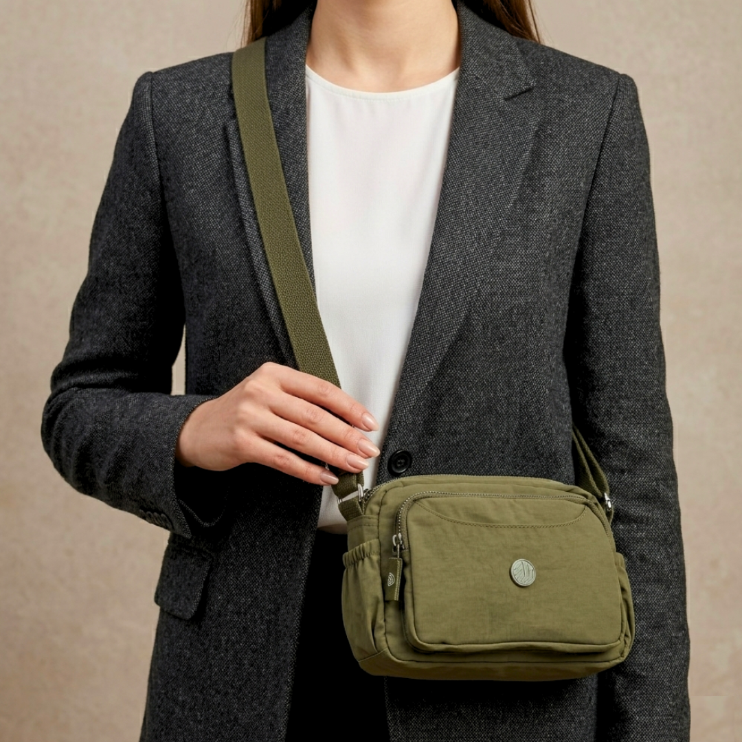 Model Carrying Military Green Sling Bag In  Front Of Beige Background.